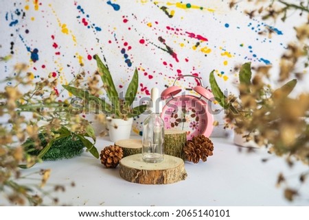 Minimalist concept displaying products. bottle on wood, dried flowers, dried leaves and pine flowers on abstract background
