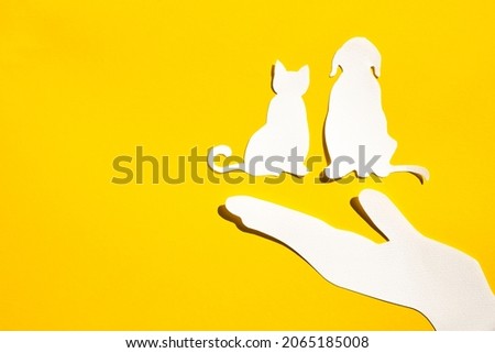Paper silhouette of a cat and dog on a yellow background. Flat lay, place for text. Veterinary or animal care.