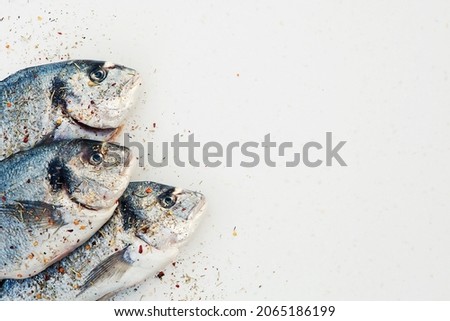 Fresh fish Gilthead bream (Sparus aurata, Dorado) with herbs and spices on white background. Healthy eating concept. Top view, copy space. horizontal image