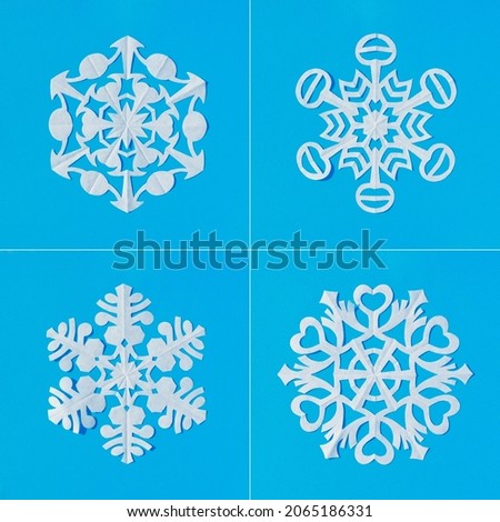 Set of white snowflakes cut out from tracing paper on a blue background