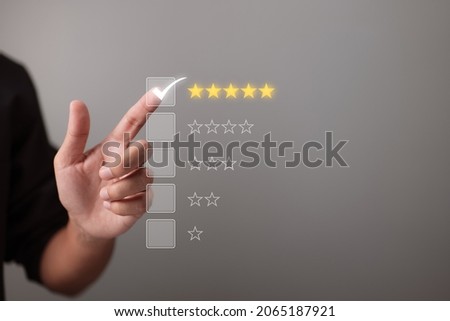 Hand touching and giving five yellow stars indicates the highest level of customer satisfaction and evaluation for a high-quality product and service. Royalty-Free Stock Photo #2065187921