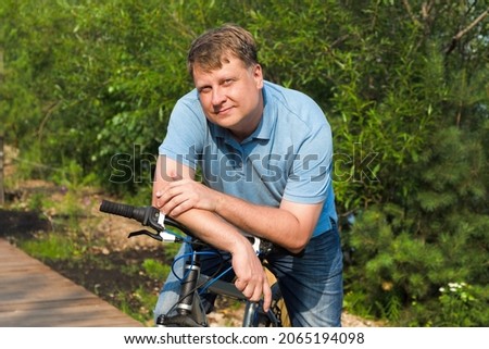 Portrait of adult male blond 40-44 years old with a wide smile sitting on a bicycle. Royalty-Free Stock Photo #2065194098