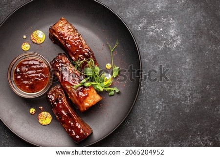 Grilled ribs with sauce and herbs on a black plate Royalty-Free Stock Photo #2065204952