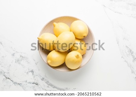 Several yellow bright lemons in a plate on a light background. Bright citruses.