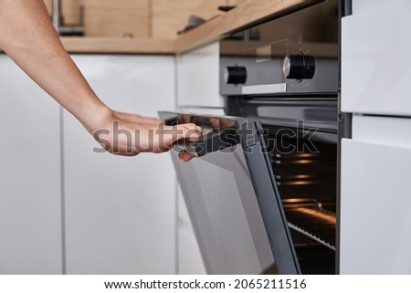 Woman hand open electric oven door with handle. Homemade cooking. Kitchen appliance Royalty-Free Stock Photo #2065211516