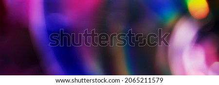 Defocused film texture background with colored lights on dark background. Blurred rainbow color light flare for photo effects