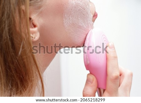 Young woman use facial massage pink brush