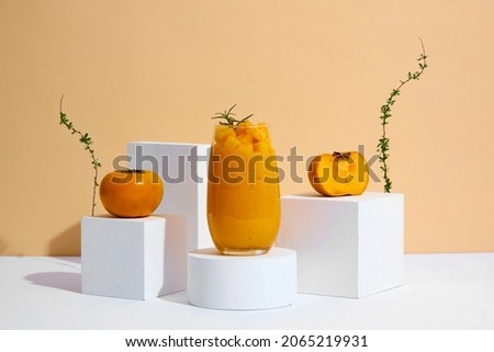 Front view of persimmon frappe with  circle , square podium , flowers in trendy  almond background for food advertising 