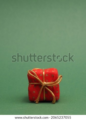 Red gift box on a green background with space for your text or image, seasonal holiday concept