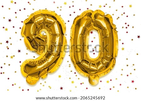 The number of the balloon made of golden foil, the number ninety on a white background with multicolored sequins. Birthday greeting card with inscription 90. Anniversary concept. Celebration event.