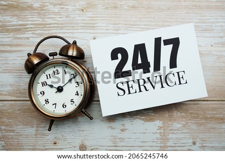 24-7 Service text and alarm clock on wooden background
