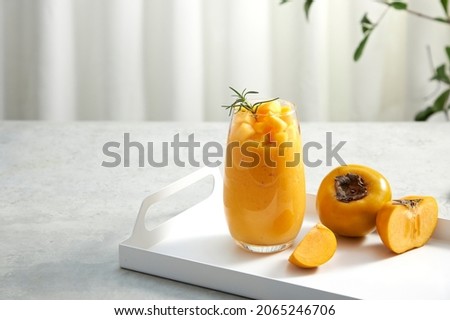 Front view of a tray with persimmon and persimmon frappe , green leaf in white curtain background for food advertising 