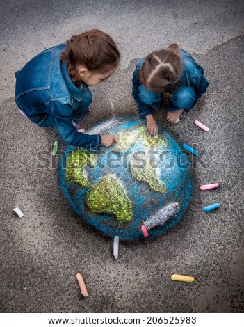 Top view shot of two girls drawing realistic Earth image with chalks on ground