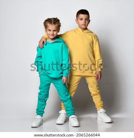 Studio portrait of a cool little boy and girl dressed in stylish bright sports suits with sweatshirts and pants on a white background. Children's sports style concept. Banner. Royalty-Free Stock Photo #2065266044