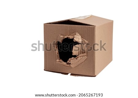 A damaged cardboard box with a large ragged hole in the wall. Insurance and indemnification Royalty-Free Stock Photo #2065267193