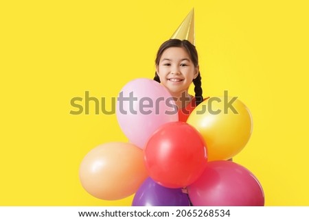 Cute little girl with balloons celebrating Birthday on color background