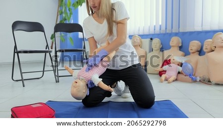 Instructor performs CPR on baby training doll. Woman instructor show how to do CPR on a doll dummy for cardiopulmonary reanimation training. Royalty-Free Stock Photo #2065292798