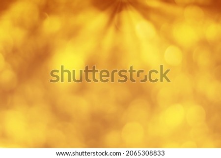 Blurred bokeh background image of bright yellow foliage and sunbeams in autumn. Abstract backdrop for design.