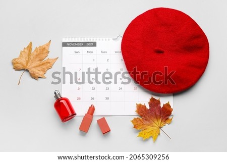 Calendar with female accessories and autumn leaves on light background