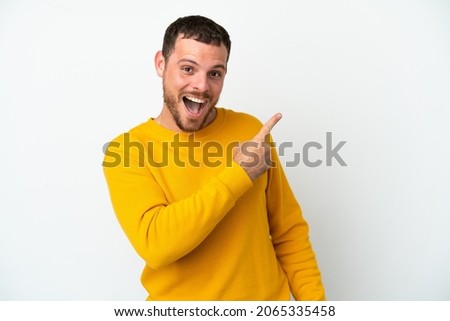 Young Brazilian man isolated on white background surprised and pointing side