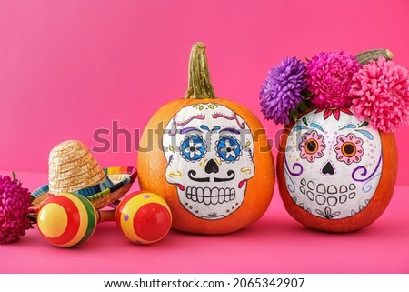 Pumpkins with painted skull on color background. Celebration of Mexico's Day of the Dead (El Dia de Muertos)
