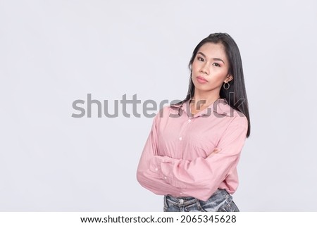 A serious young lady wearing a pink blouse. Crossing her arms and meaning business. Royalty-Free Stock Photo #2065345628
