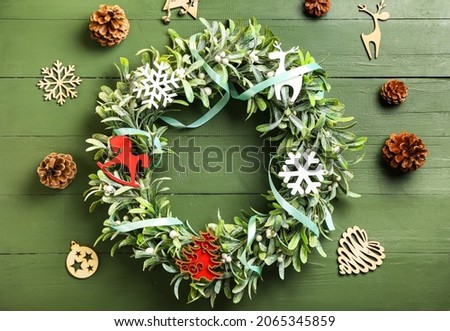 Beautiful mistletoe wreath on green wooden background