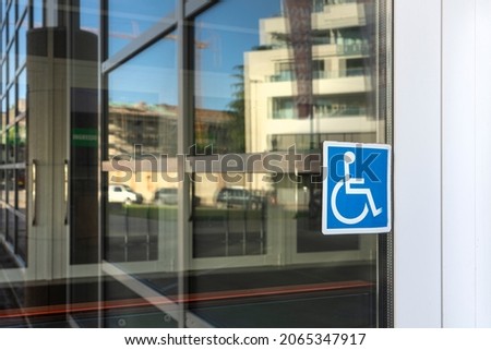 the sticker indicating the entrance for the disabled on the glass of a door