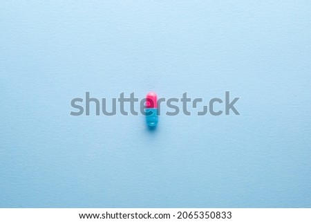 Multi-colored pills.Pink and blue pills on a light blue background.Different pills are lined up in turn.Pills for women.Medications of different colors.Pharmacy.Antibiotics.Autumn vitamin deficiency