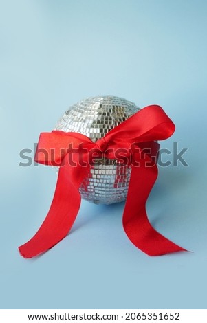Minimalistic Disco ball with red ribbon bow. New Year party invite card. Creative Christmas concept. Vertical orientation 