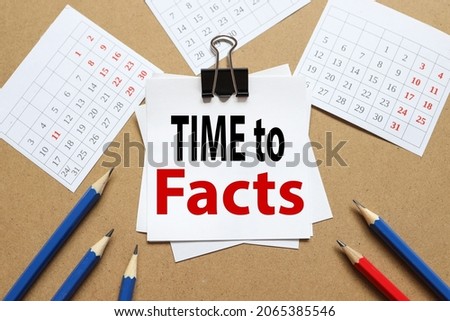 Time for Facts. white stickers are secured with a clerical clip. with pencils and calendar. Note paper with space for text on brown craft background.