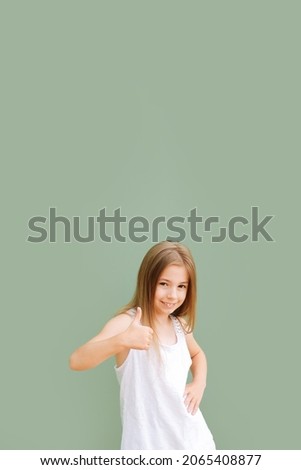 Portrait of a cheerful little girls schoolgirl in a white t-shirt on an olive background laughs smiling
