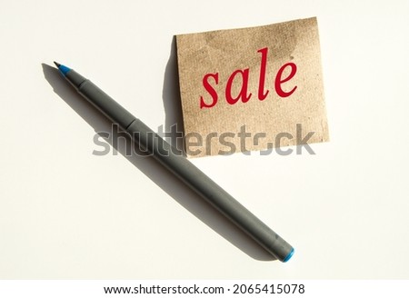 The word sale is written on brown wrapping paper, there is a pen next to it.
