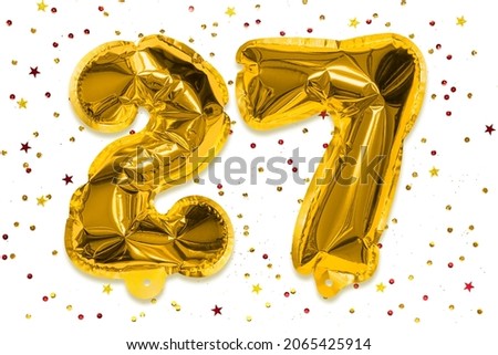 The number of the balloon made of golden foil, the number twenty-seven on a white background with multicolored sequins. Birthday greeting card with inscription 27. Numerical digit, Celebration event.