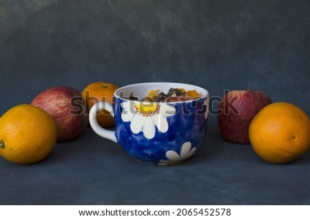 bowl of fruit salad, with oranges and apples around, with rustic gray background