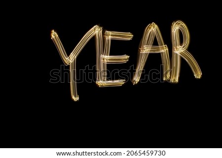 The word 'year' written against black background with long exposure yellow light. Happy new year concept photo.