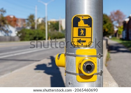 Yellow pedestrian push button sign on traffic signal pole at crosswalk in Ottawa street, Canada