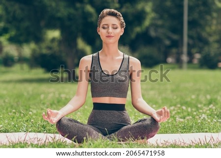 Photo of serene sincere peaceful sportswoman sit mat do yoga wear grey top nature park garden outdoors