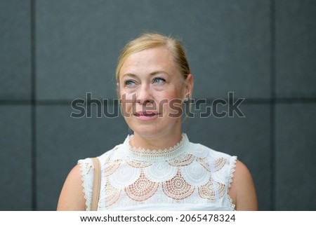Serious blond woman with smiling blue eyes dressed in a stylish white lacy top Royalty-Free Stock Photo #2065478324