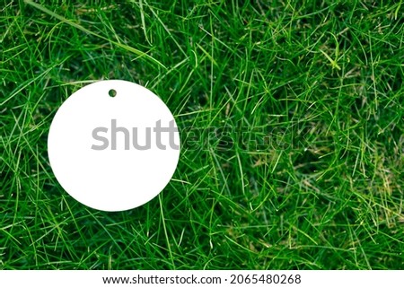 creative layout composition frame of green grass lawn with one white cardboard round isolated tag flat lay and copy space for logo. 