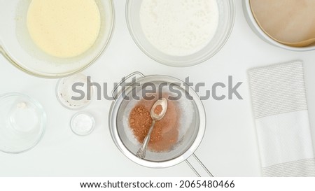 Whipped whites, whipped yolks, and cocoa powder close up on kitchen table. Step by step chocolate cake recipe, flat lay, white kitchen table background, copy space