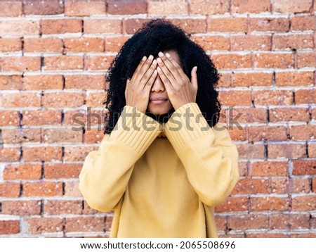 Young African American woman with hands covering her eyes 