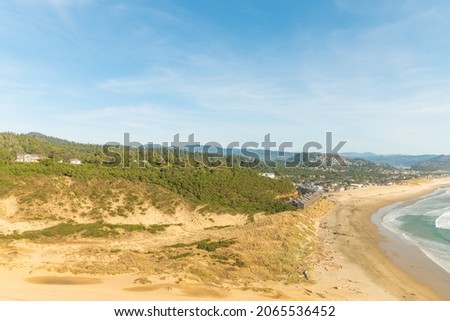Wild deserted ocean shore. Sandy hills. Strip of the ocean, blue sky. Sparse vegetation. There is no one in the photo. Calm scenes. Tourist destinations, postcard, advertising.