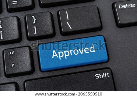 Approved blue key on the black pc keyboard. Concept of business project approval stage. Computer notebook enter key with the word Approved. Message on the enter button of keyboard. Close-up.