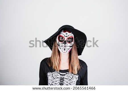 woman wearing mexican face mask during halloween celebration. skeleton costume and black stylish hat. Halloween party concept