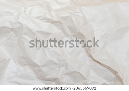 Background texture of crumpled kraft paper. White uneven background. Cracks and creases on paper. Uneven texture.