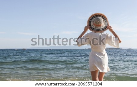 Portrait of young woman wearing linen kimono dress and big straw hat on the beach	 Royalty-Free Stock Photo #2065571204