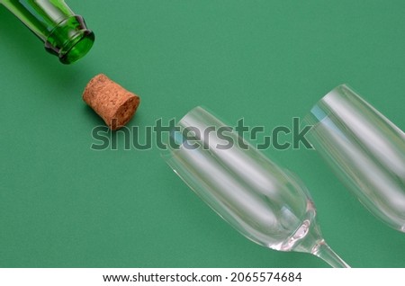 an open bottle and two empty glasses