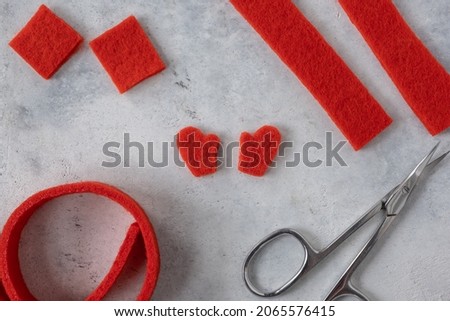 Making New Year's red felt mittens with your own hands. Mittens cut out of felt and scissors. Concept for making Christmas toys or greeting card. New Year's crafts with children DIY.