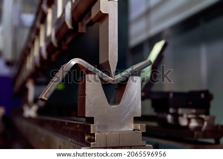 Work on a CNC bending machine in a factory. Sheet metal bending on a high-precision metal bending machine. Royalty-Free Stock Photo #2065596956